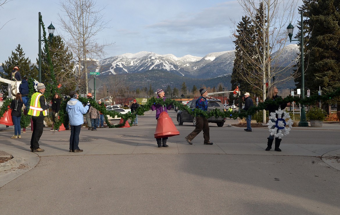 Volunteers helped hang the winter decorations downtown Sunday morning. For more than 50 years the decorations have brightened Whitefish. (Heidi Desch/Whitefish Pilot)