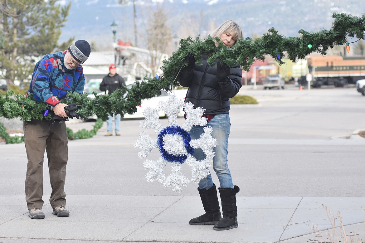 Volunteers helped hang the winter decorations downtown Sunday morning. For more than 50 years the decorations have brightened Whitefish. (Heidi Desch/Whitefish Pilot)