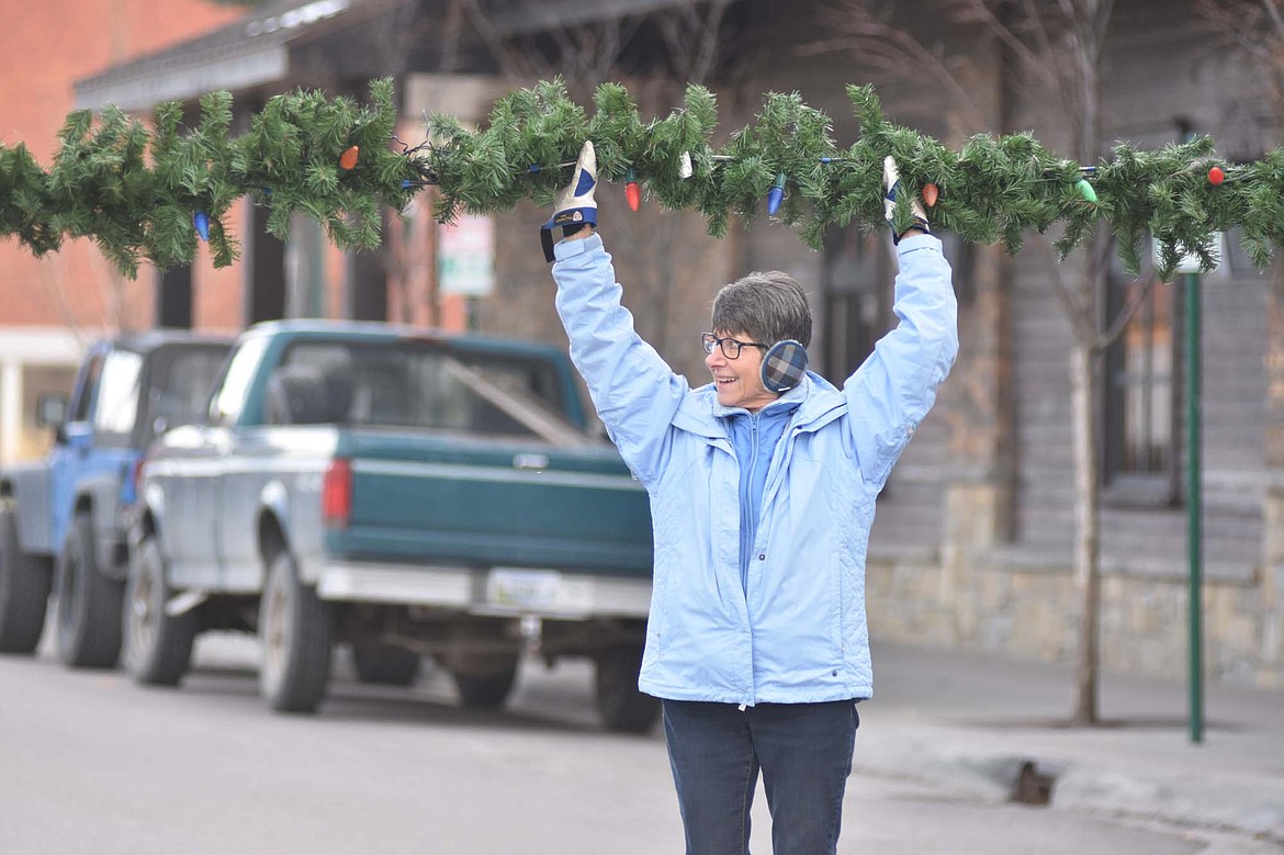 Volunteers helped hang the winter decorations downtown Sunday morning. For more than 50 years the decorations have brightened Whitefish. (Heidi Desch/Whitefish Pilot)