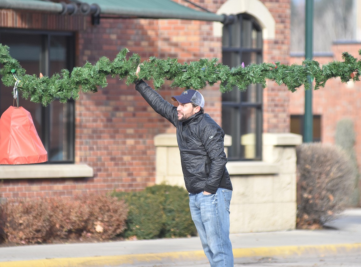 Volunteers helped hang the winter decorations downtown Sunday morning. For more than 50 years the decorations have brightened Whitefish. (Heidi Desch/Whitefish Pilot)