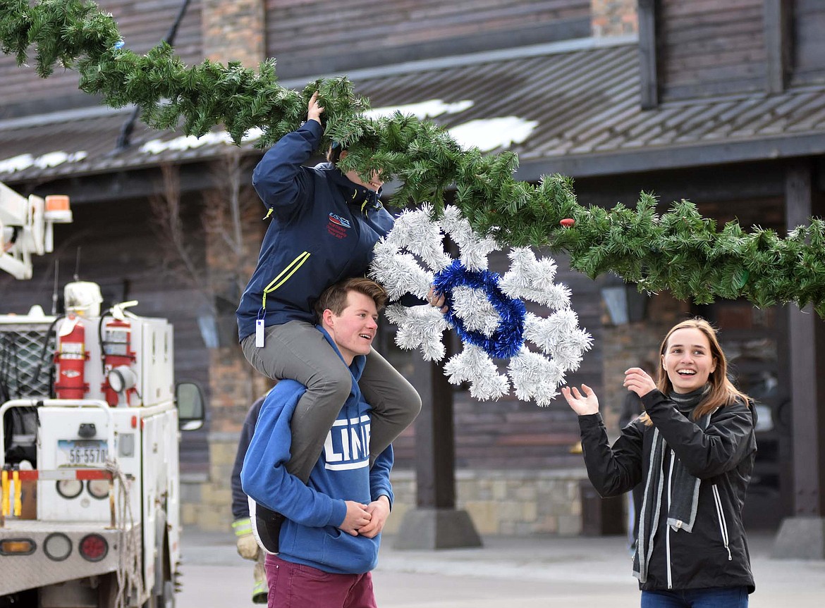 Volunteers helped hang the winter decorations downtown Sunday morning. For more than 50 years the decorations have brightened Whitefish. (Heidi Desch/Whitefish Pilot)