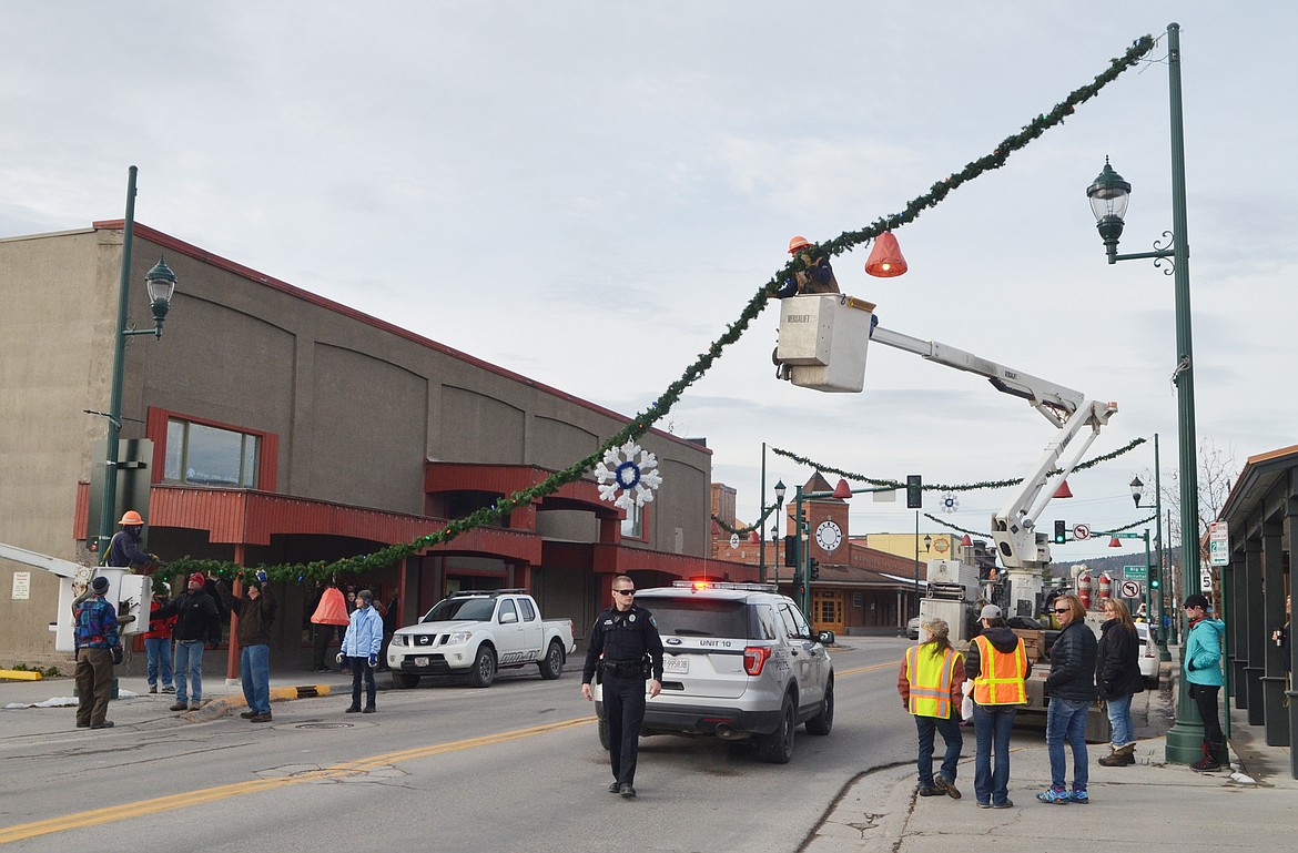 Volunteers helped hang the winter decorations downtown Sunday morning. For more than 50 years the decorations have brightened Whitefish. (Heidi Desch/Whitefish Pilot)