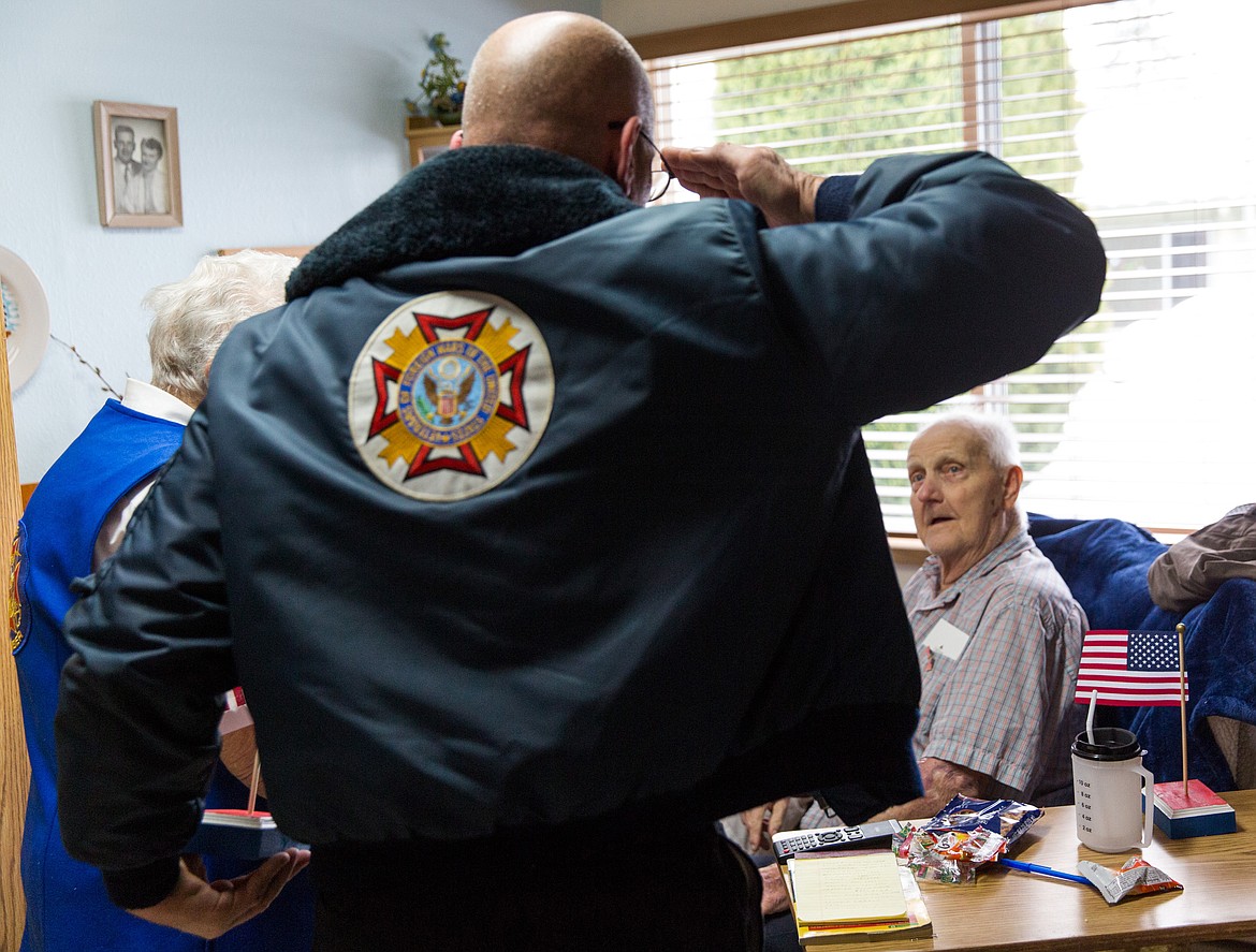 Gary Zoutte, commander of Libby VFW Post No. 1548, salutes veteran Russell Christopherson at Libby Care Center Saturday, Nov. 11. Zuotte and Stella Sharp, left, were among a handful of VFW members who gave out flags to the center&#146;s veterans in honor of Veterans Day. (John Blodgett/The Western News)