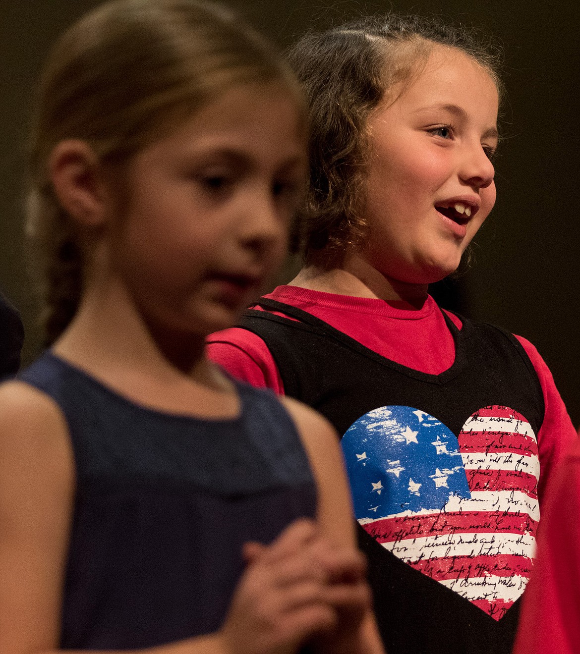 Kootenai Valley Christian School first grader Lilyanna Harcourt, left, and second grader Isabella Covey sing in honor of veterans at Libby Christian Church on Friday, Nov. 10, 2017. (John Blodgett/The Western News)