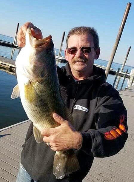 Pete Fisher photo - Russ Anderson shows a 7-pound Largemouth bass he caught off the MarDon Dock. Russ released this lunker after the pic.