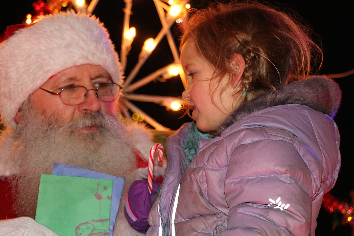 (Photo by CAROLINE LOBSINGER)
A young fan gives Santa Claus her decorated Christmas wish list as she met the jolly old elf at Friday's Christmas tree lighting ceremony.