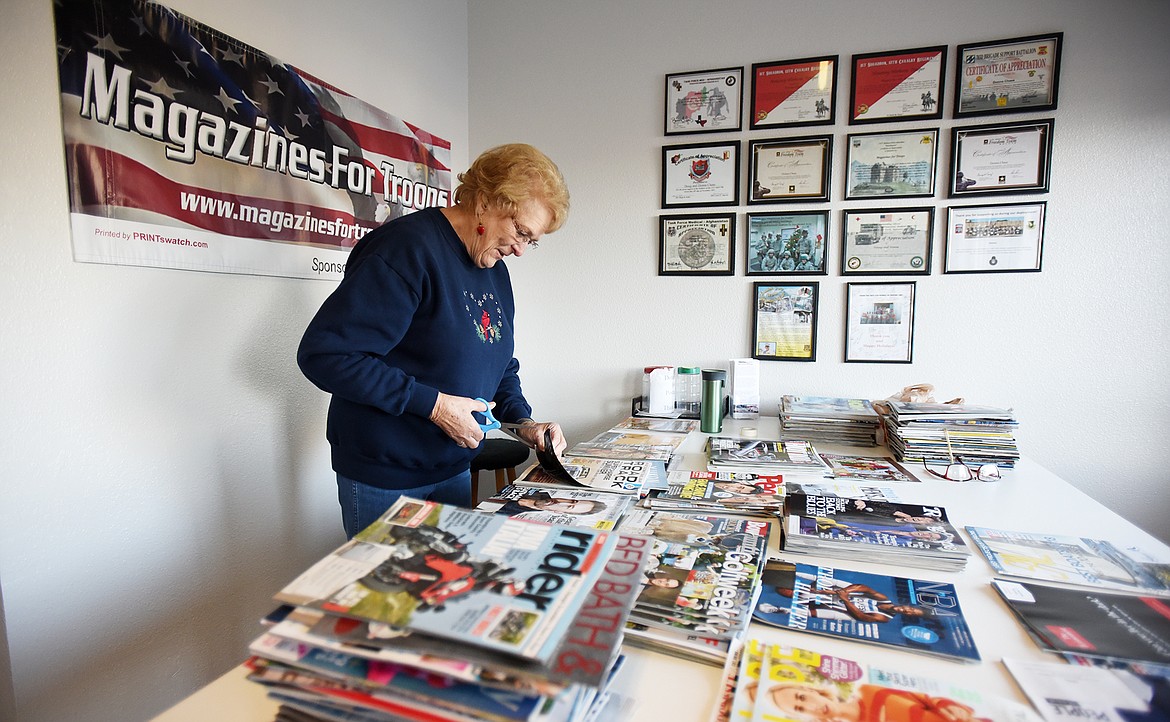 Caroline Casteel cuts shipping labels off magazines at Magazines for Troops on Tuesday, November 22, in Lakeside. Magazines that is donated from a subscription have names and addresses and these must be removed before they are sent overseas, removing labels is one of the ways volunteers can help Magazines for Troops which reached its tenth anniversary this fall.(Brenda Ahearn/Daily Inter Lake)