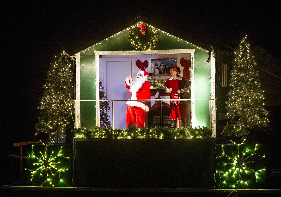 LOREN BENOIT/PressSanta and his elf friend greet children on the Journey to the North Pole cruise Tuesday night.