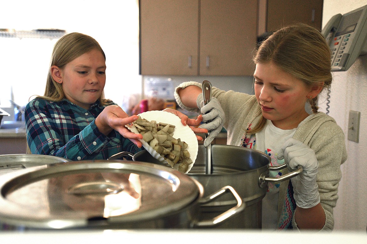 Maia Dodge, left, adds potatoes to the school&#146;s version of stone soup while Marlo Carpenter stirs at Kalispell Montessori Elementary on Tuesday, Nov. 21. The stone soup meal is an annual tradition at the school as Thanksgiving nears. 
(Casey Kreider/Daily Inter Lake)