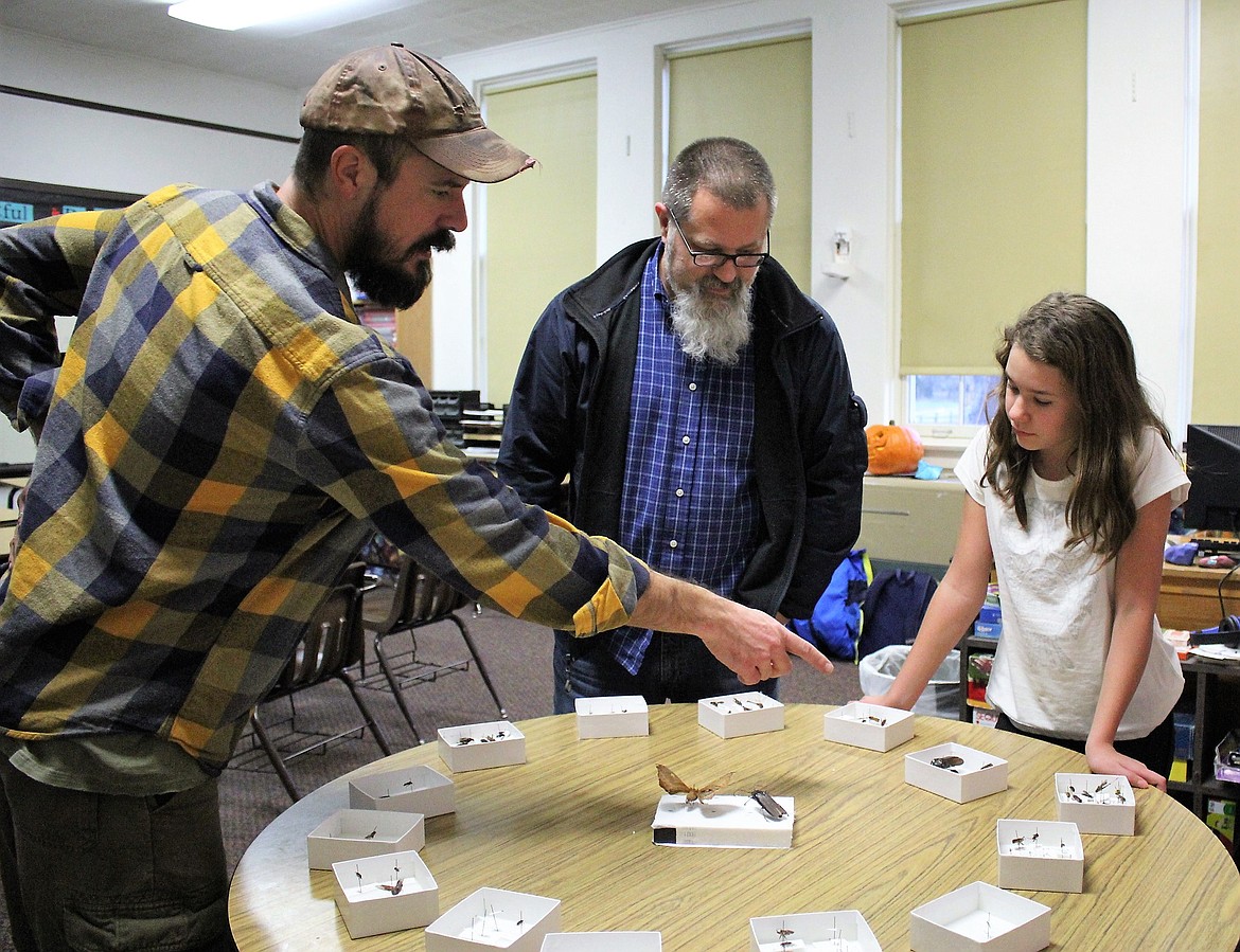 Alberton afterschool student Rayleen shows her dad the bug collections students made with teacher Aaron Adams (left) during &#147;Lights On&#148; held Oct. 26. Federal funding for afterschool programs was increased by $100 million for 2018. (Kathleen Woodford/Mineral Independent)