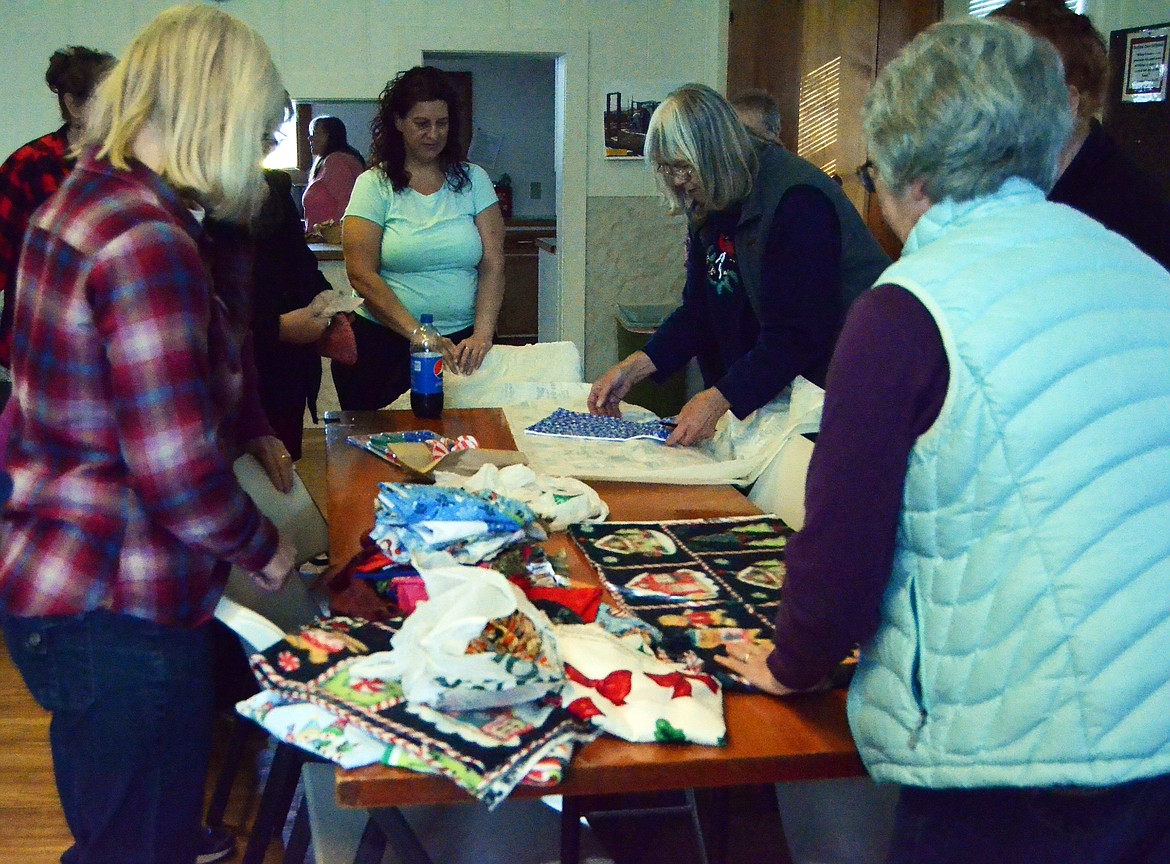 Local members start thir event by cutting patterns to use on the oile of Chritmas fabrics (Erin Jusseaume/ Clark Fork Valley Press)