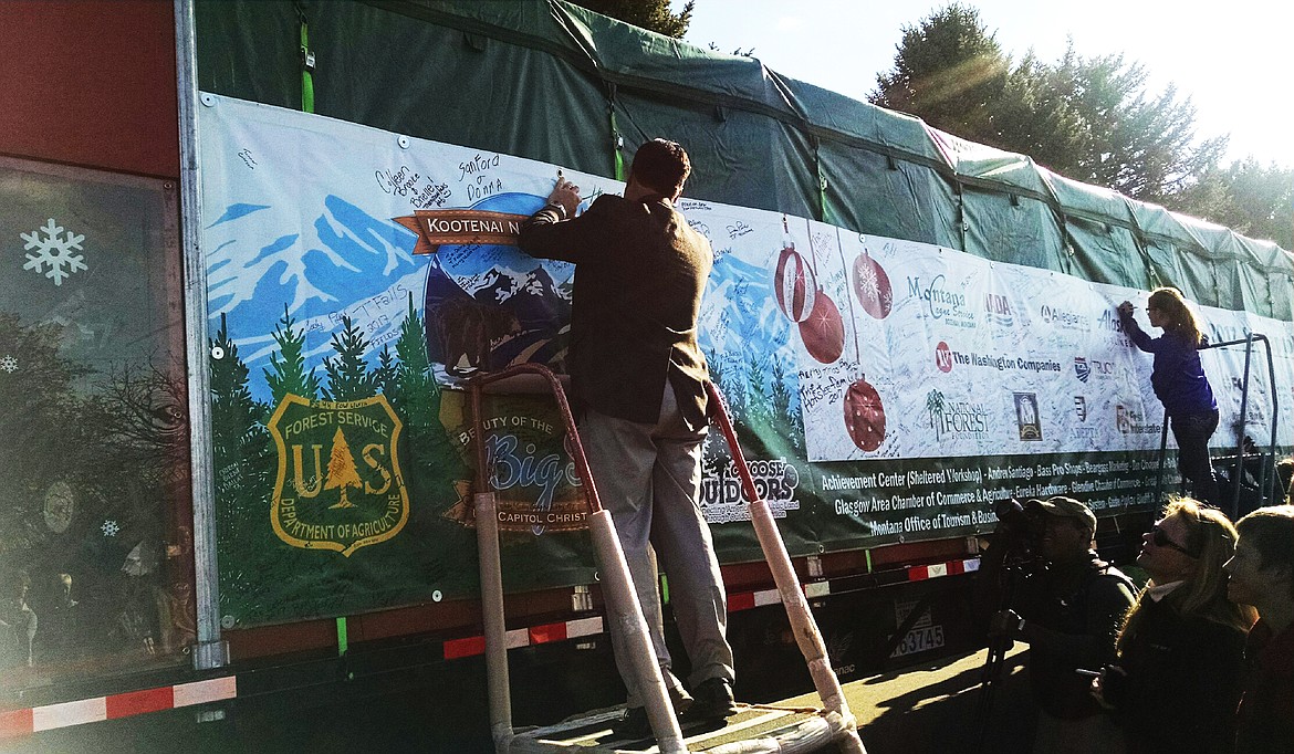 Thom Chisholm takes a turn signing the banner on the truck (Clark Fork Valley Press)