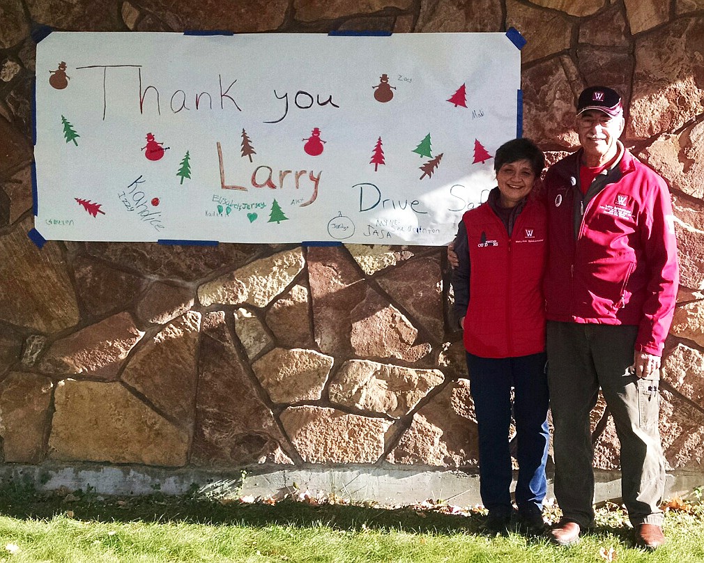 Larry and Mary Ann Spiekermeier pose next to a sign from one of the local classes at the Plains School to wish Larry and the truck a safe journey (Clark Fork Valley Press)