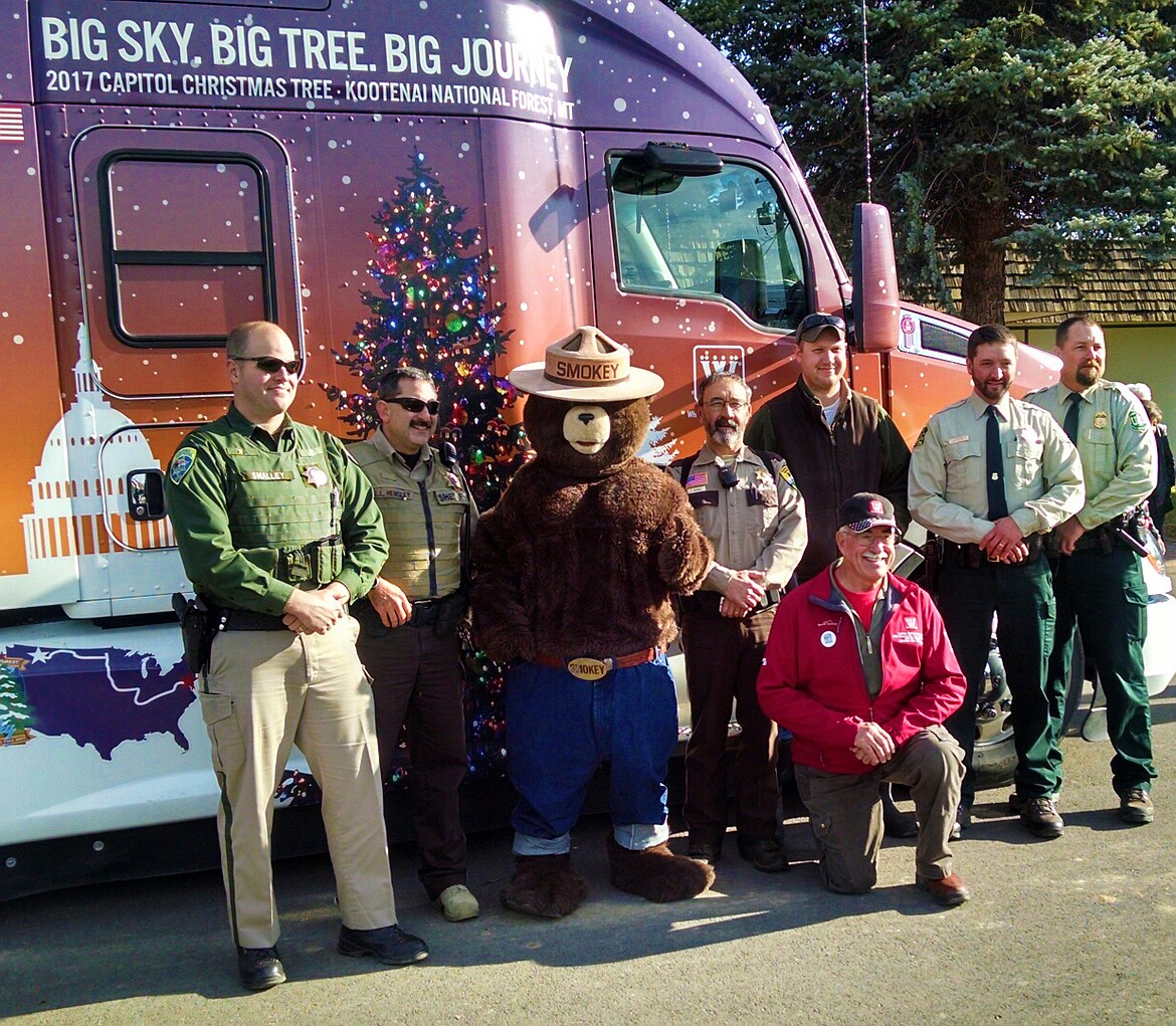 The team that escorted the truck hualing the U.S. Capitol Christmas Tree to Plains poses for a photo on Wednesday. From left, Shawn Smalley, Montana Highway Patrol; Lanny Hensley, Sanders County Undersheriff; Smokey Bear; Tom Rummel, Sanders County Sheriff; Larry Spiekermeier; Zach Rehbein, Montana Highway Patrol; Chad Kashmier, Forest Service; and Nathan Snead, Forest Service. (Clark Fork Valley Press)
