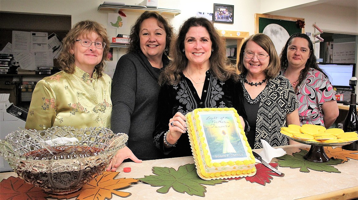 Shana Williams (far left), librarian Florence Evans, author Robin Gainey (holding cake), director, Guna Chaberek, and librarian Echo Hayder (far right) held a presentation to celebrate Gainey&#146;s new novel, &#147;Light of the Northern Dancers,&#148; at the Mineral County Library on Nov. 13. (Kathleen Woodford/Mineral Independent).