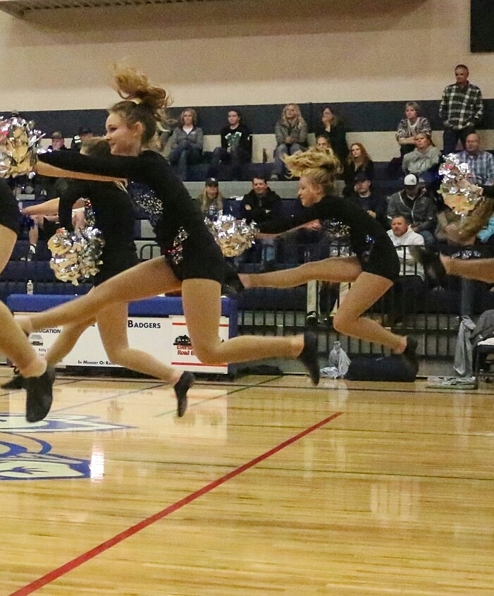 Isabella Bennet and Avery Pluid perform a hurdler jump during the dance routine at the girls basketball game.