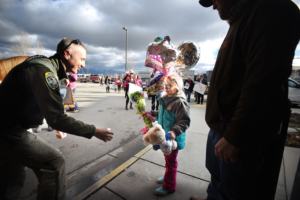 Montana Highway Patrol Trooper John Underwood gives a teddy bear to Willow Henke, 6, outside The Rock at Kalispell Regional Medical Center on Wednesday, November 29. Henke arrived on horseback for her final chemo treatment.&#160;(Brenda Ahearn/Daily Inter Lake)