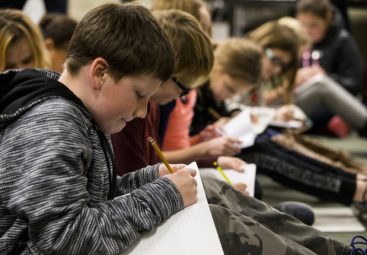 LOREN BENOIT/PressTharan Lutner writes a short story Friday afternoon at Fernan Stem Academy. Children's author Gary Hogg came to school to help students structure their stories.