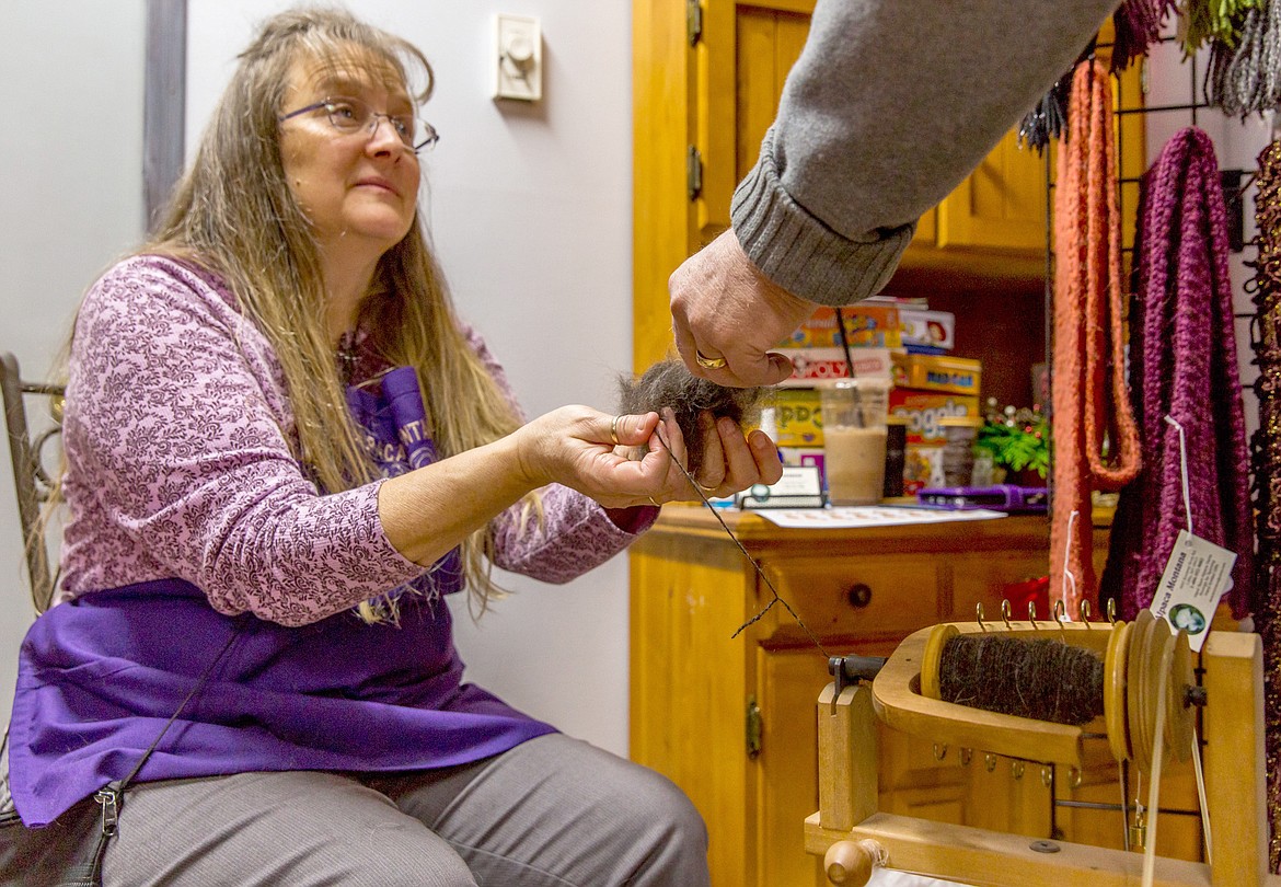 Shauny Fisher of Alpaca Montana in Libby lets a man feel the texture of dog hair she was spinning during a Dicken’s Fair held Saturday at AuntT’s Coffee Corner in Libby. Because dog hair tends to be short, she mixes it with alpaca. (John Blodgett/The Western News)