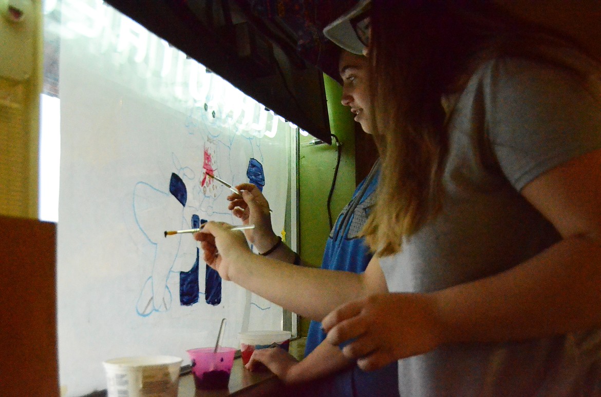 Leena Muckler and Maykenzi Blood paint the window of the local movie theater.
