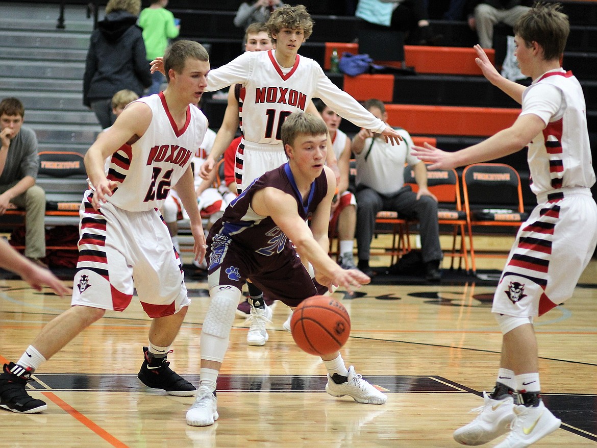 Freshman Bryan Mask, tries to break free from Noxon players during their season opener on Friday in Frenchtown. The Cats lost 62-51. (Kathleen Woodford/Mineral Independent).