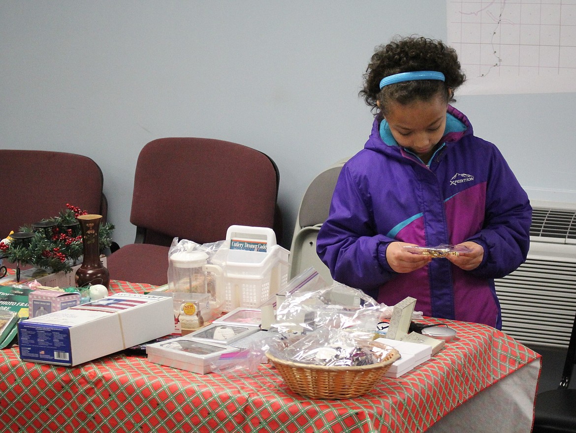 Eve Farnsworth, 8, picks out a gift for her mother at the Parent&#146;s Gift Table hosted by the local Women In Timber group. Tables were set up on Dec. 2 at the Superior Volunteer Fire Department. (Kathleen Woodford/Mineral Independent)