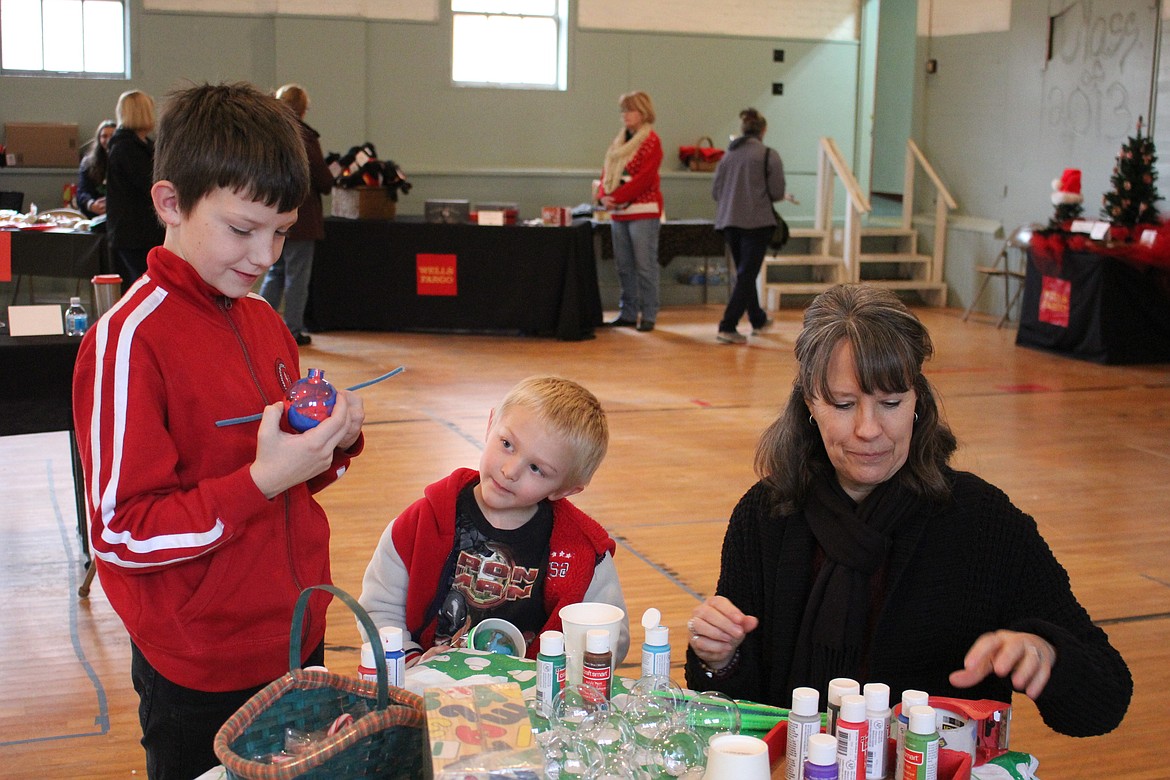 Kaleb Park, 10, makes a Christmas bulb with little brother, Dominic Mancini, 5, at the Holiday Stroll in Superior with Parents as Teachers coordinator, Janet Smith.