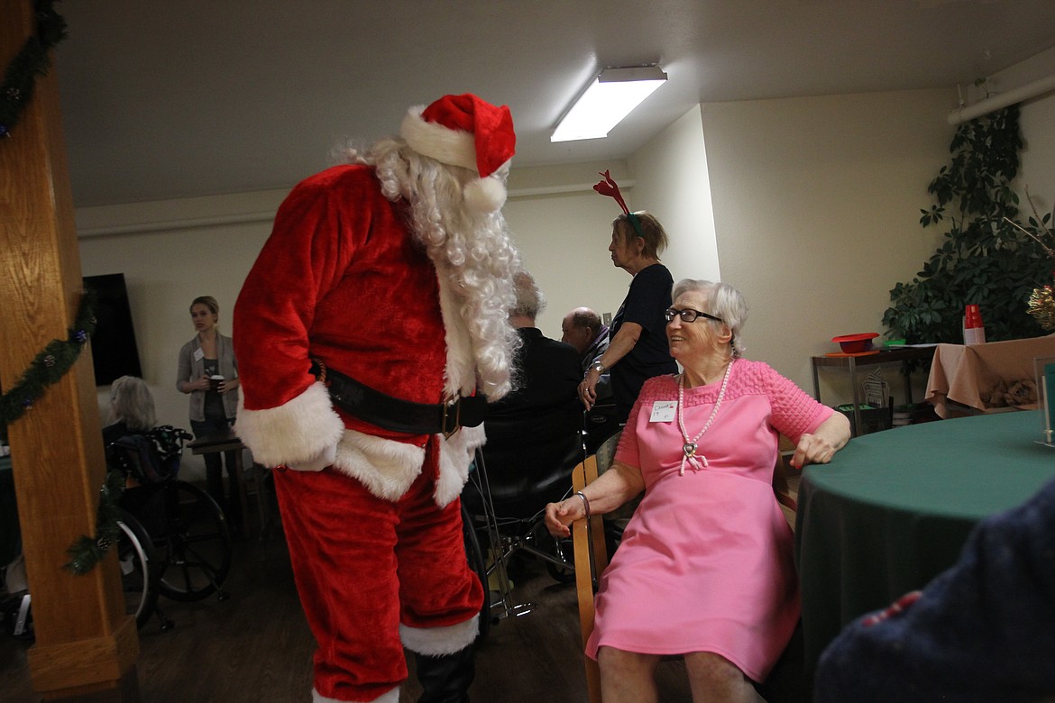 Santa asks a smiling Dorothy Nickel if she hails from Kansas during a Christmas party in the Coeur d'Alene Health and Rehabilitation Center on Thursday. The party, thrown by Silver Angels for the Elderly, included games, crafts, time with Santa, music and holiday treats. (DEVIN WEEKS/Press)