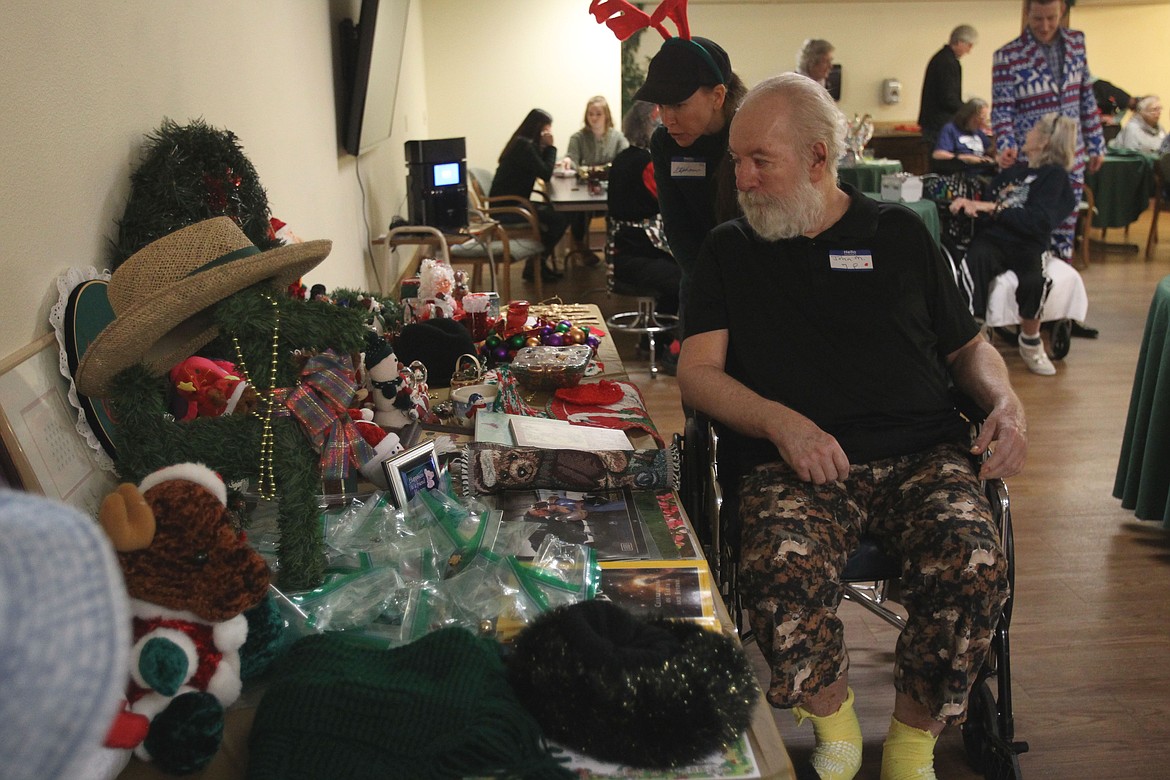 John Maloney, a resident of Coeur d'Alene Health and Rehab, scopes out a table of trinkets and treasures with Silver Angels for the Elderly volunteer Stephanie Hunter during a holiday party Thursday. Maloney picked out a small stuffed Santa as his game prize. &quot;It's kinda fun,&quot; he said with a grin. (DEVIN WEEKS/Press)