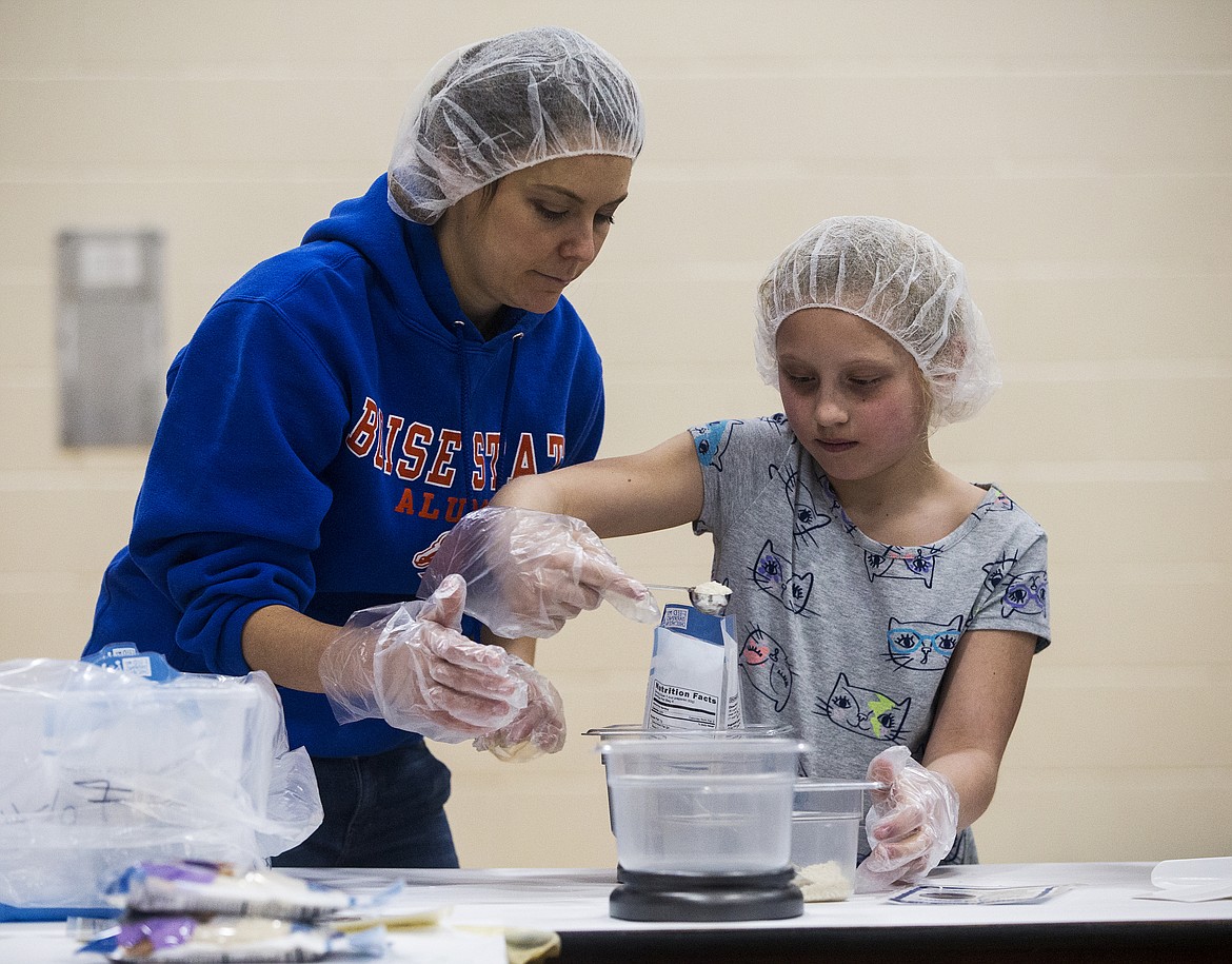 Holli Reavis, 8, and her aunt, Rita Roth, pour rice into a MobilePack Friday evening at Skyway Elementary School. Hundreds of volunteers gathered to fill packs for the Feed My Starving Children MobilePack program to reach hungry children around the world. (LOREN BENOIT/Press)