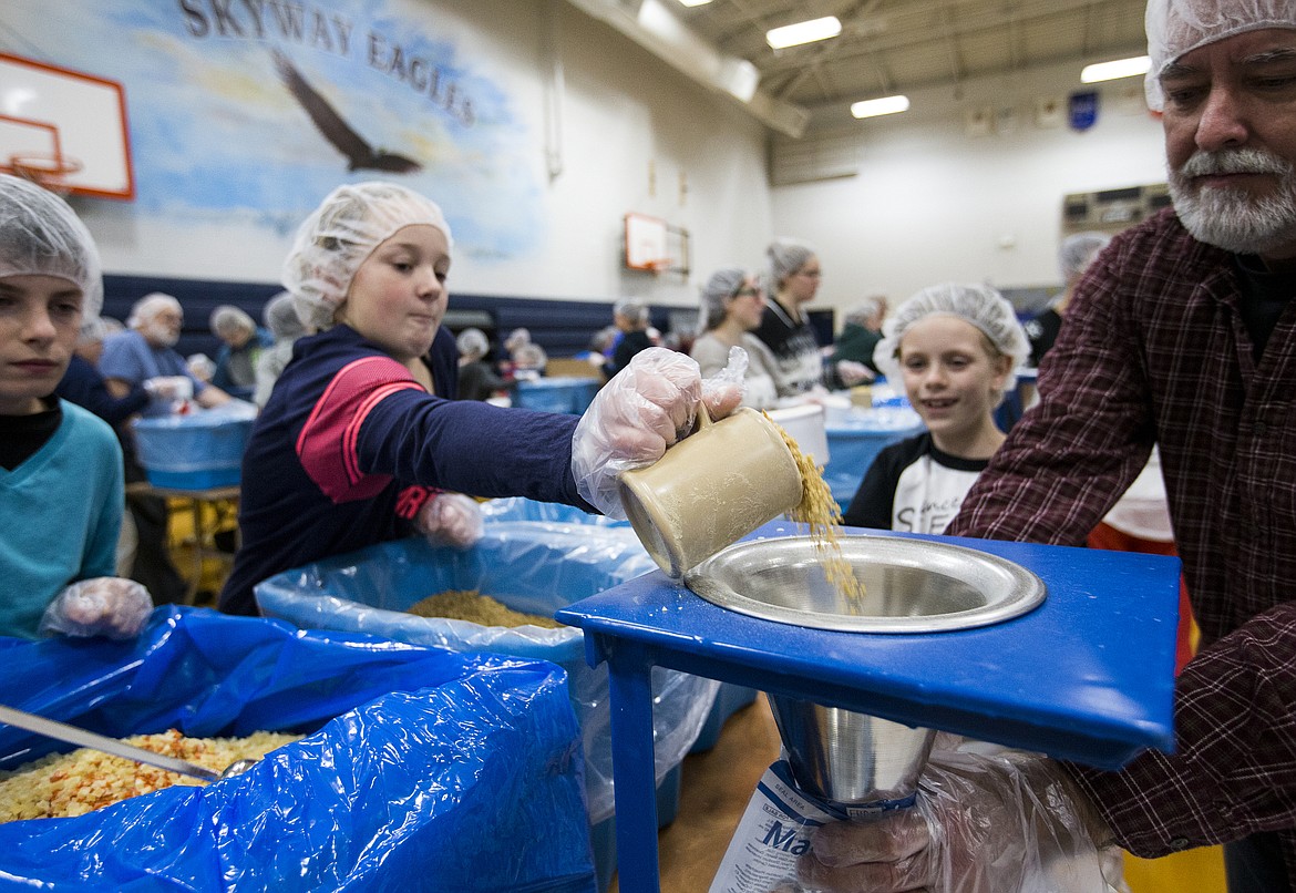 LOREN BENOIT/Press
Volunteer Kamryn Pickford pours soy into a bag for the Feed My Starving Children MobilePack program Friday evening at Skyway Elementary School.