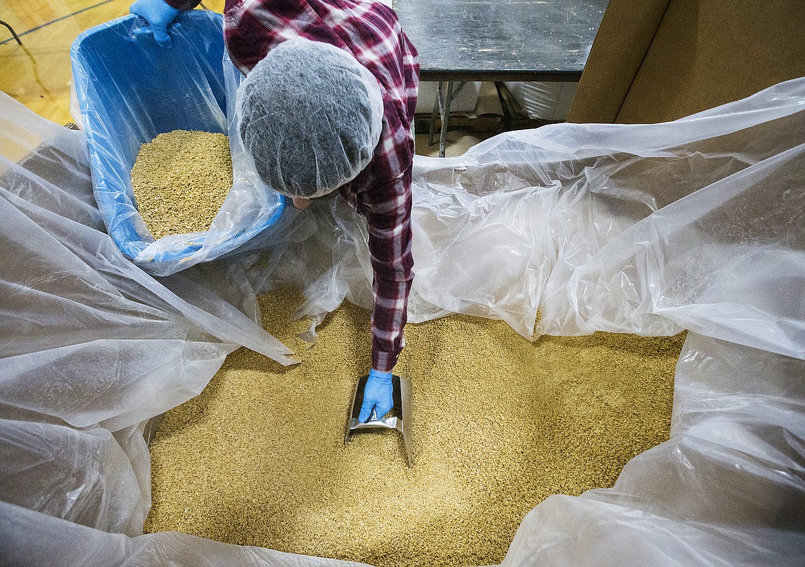 Austin Taylor scoops up soy to into a smaller bin during MobilePack's Feed My Starving Children program Friday evening at Skyway Elementary School. (LOREN BENOIT/Press)