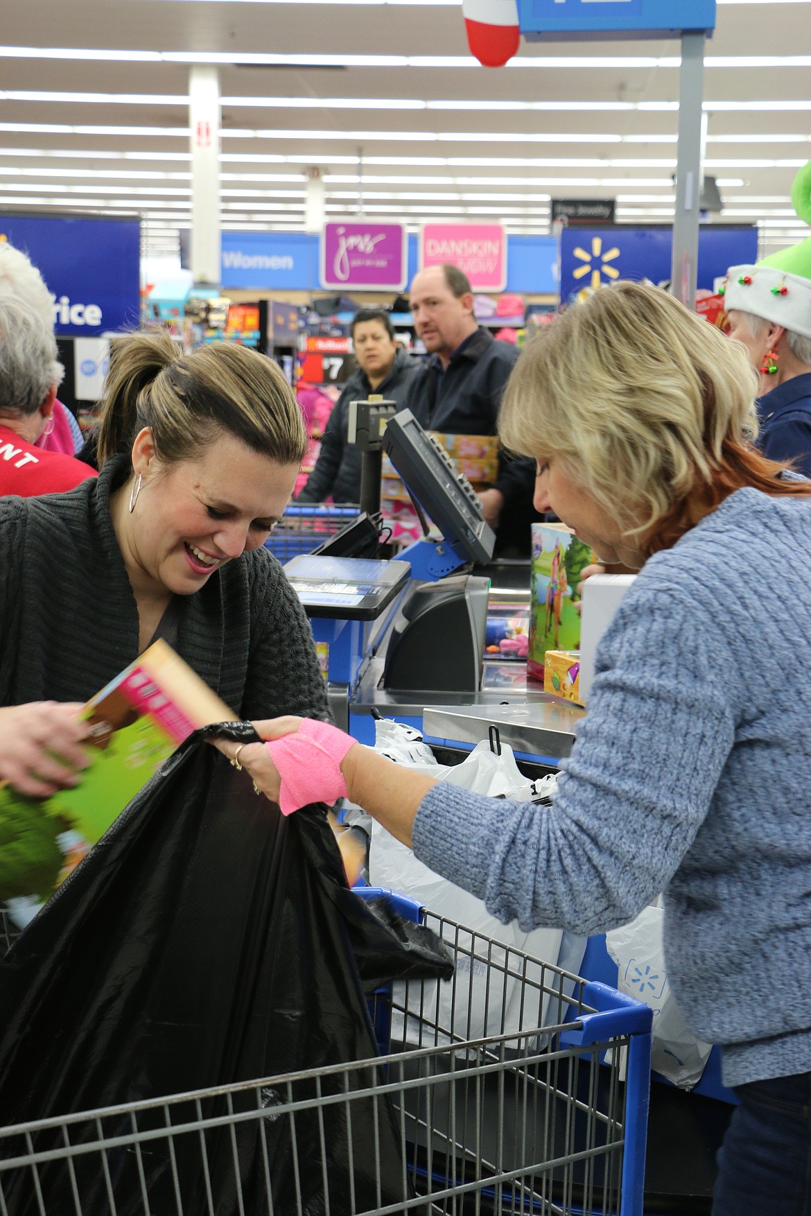 (Photo by MARY MALONE)
Lindsay Coon laughs and she checks out after after helping the Sandpoint Lions Club purchase toys at Walmart on Dec. 7 for the club's annual Toys for Tots campaign.