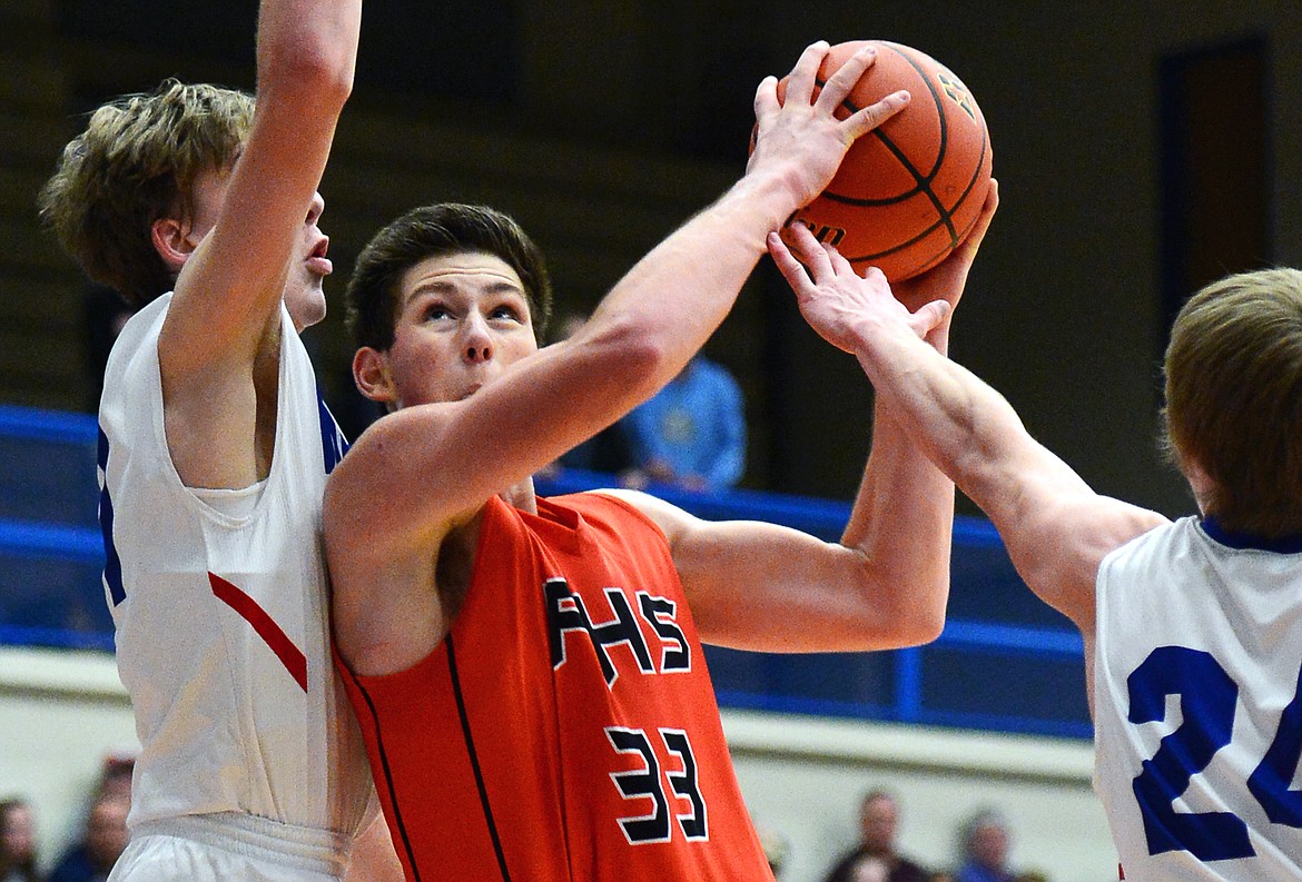 Flathead's Sam Elliot splits Columbia Falls' defenders Matthew Morrison, left, and Logal Bechtel on the way to the hoop on Saturday. (Casey Kreider/Daily Inter Lake)