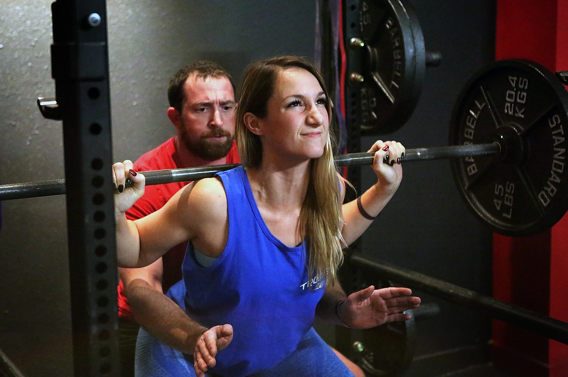 Tracy Blaylock, of Kalispell, lifts during squat practice while Aaron Cross spots her at Beast Athletes on Montana Highway 35. (Mackenzie Reiss/Daily Inter Lake)