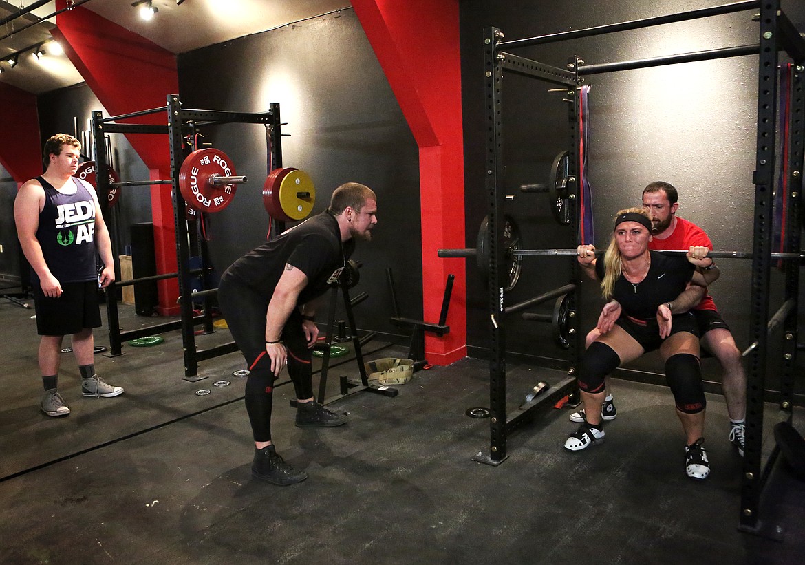 Donny Tudahl cheers on his fiance, Kristiana Konkol, while Aaron Cross spots her during a Beast Athletes Powerlifting Team practice. Tudahl opened the gym Dec. 2 and will host a grand opening Jan. 6.