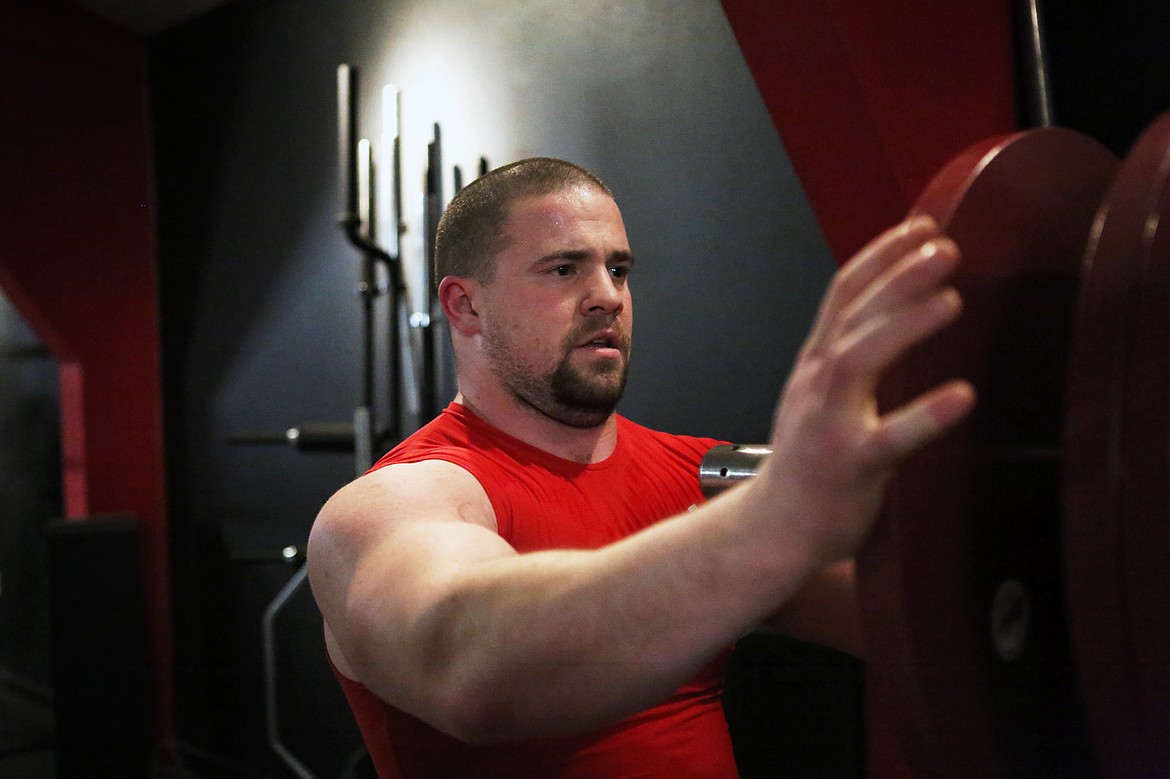 Marcus Applegate, of Columbia Falls,  loads a barbell with weights Dec. 7 during squat practice for the Beast Athletes Powerlifting Team. (Mackenzie Reiss/Daily Inter Lake)