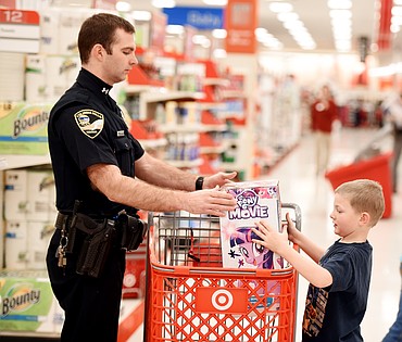 Seth Stratton of the Columbia Falls Police Department does some Christmas shopping with Mason Frink, 6.