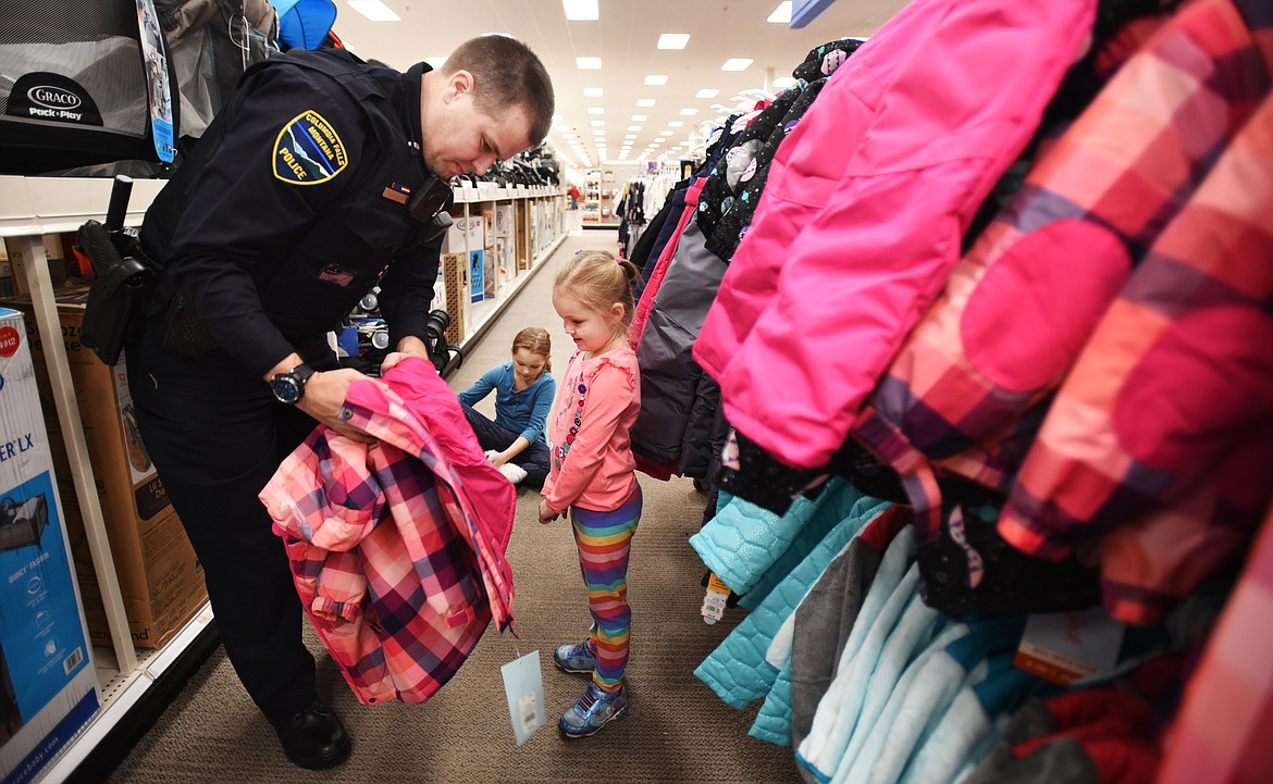 Jared Haddenham of the Columbia Falls Police Department shops for a coat with Baylie Peterson 5, as her sister Shelbie, 9, waits her turn.