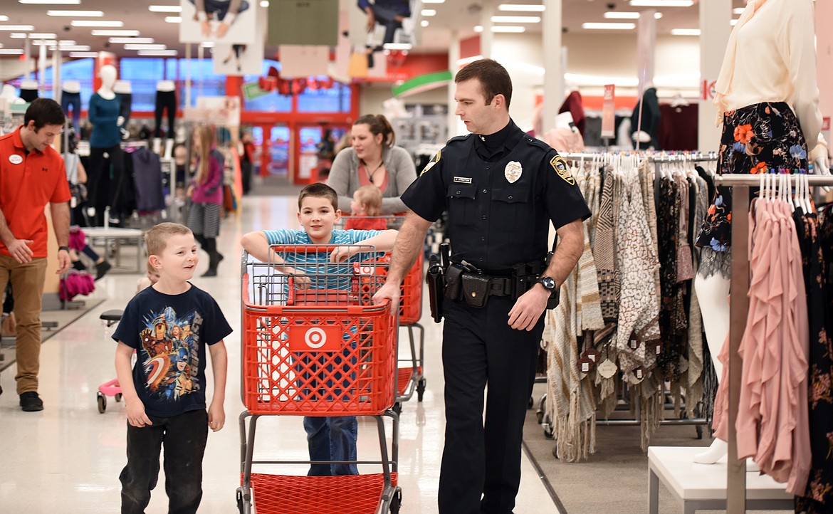 Seth Stratton of the Columbia Falls Police Department does some Christmas shopping with Mason Frink, 6, left, and his brother Malcom, 9.