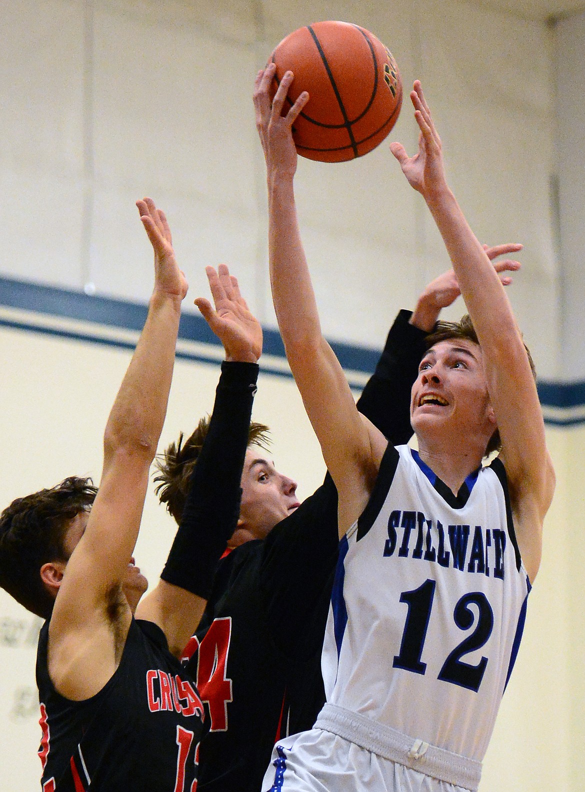 Stillwater Christian's Nicholas Sulzbacher lays in two points against Flathead Valley Homeschool defenders Caleb Gwynn (12) and Spencer Burden (24). (Casey Kreider/Daily Inter Lake)