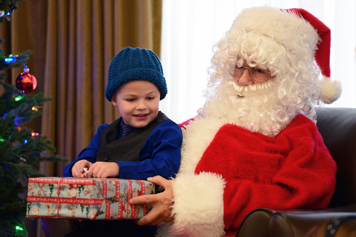 Blayde Jaeger, 5, opens presents on Santa&#146;s lap, portrayed by resident RJ Kraft, at Prestige Assisted Living in Kalispell on Wednesday, Dec. 13. (Casey Kreider/Daily Inter Lake)