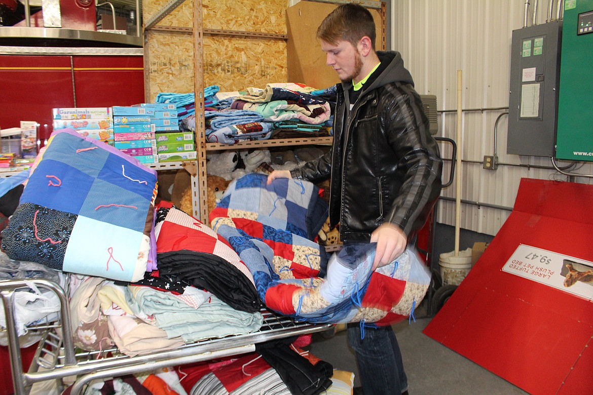 File photo
Cameron Williamson sorts and stacks handmade quilts donated for last year&#146;s Othello Christmas Basket project. Raising money for the Christmas baskets involves most of Othello, in one way or another.