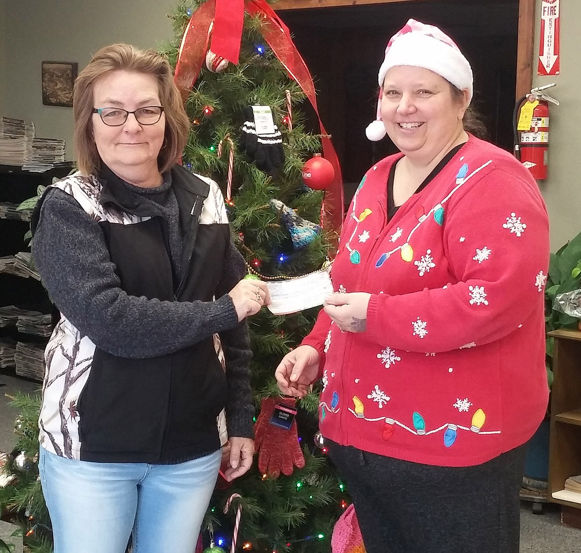 Angel Ford, right, president of the Libby VFW Ladies Auxilliary, hands a $500 check to Ronda Ames of Lincoln County Christmas to benefit its annual gift-giving efforts. (Suzanne Resch/The Western News)