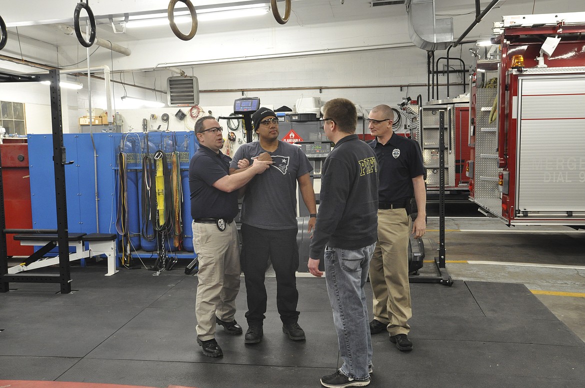 Polson Police Officer Oscar Garcia, center, volunteers during taser training while instructor Officer Jim Atkins, left, explains what Garcia will experience during the demonstration. Also pictured are Michael Hingiss, third from left, and Polson Police Department Sergeant George Simpson, far right. (Ashley Fox/Lake County Leader)