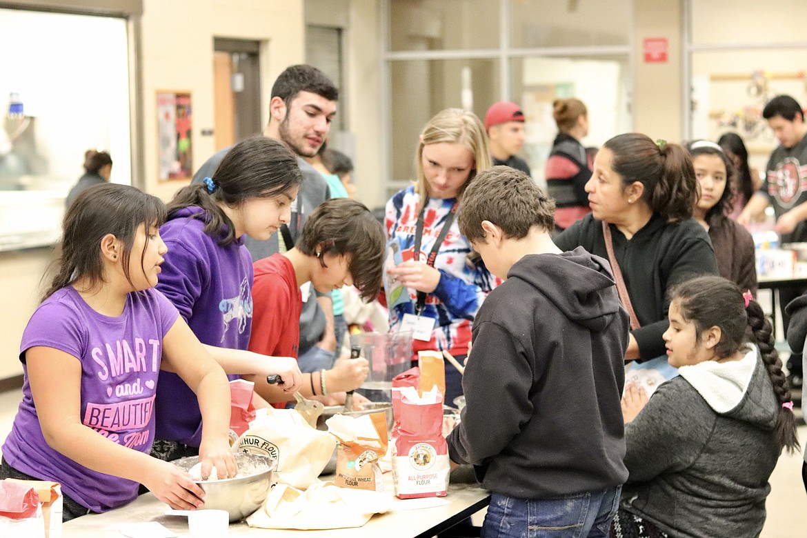 Marcos Zuniga photo - High school volunteers offer support to students and family members as they make bread during Bread Baking and STEM Activity Night at Wahitis Elementary.