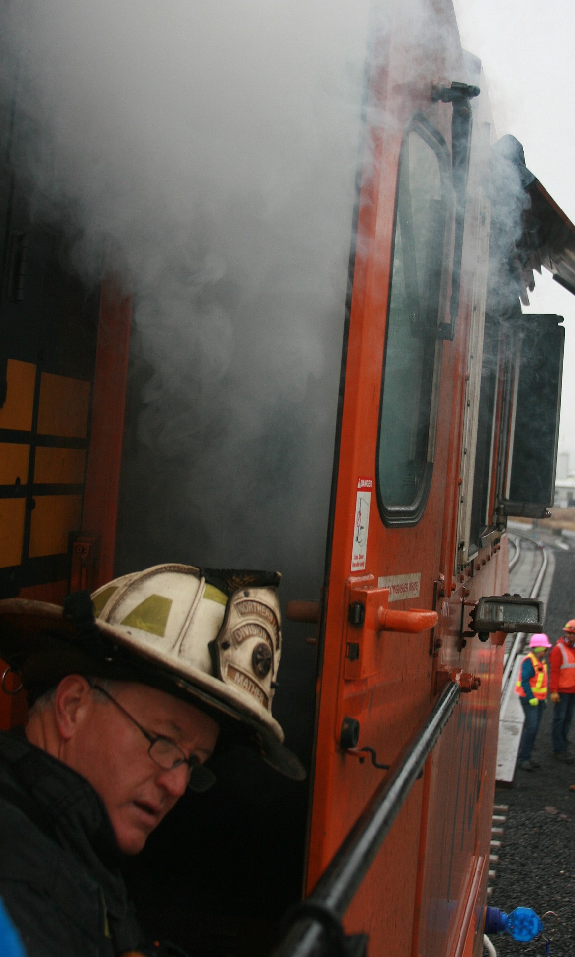 Northern Lakes Fire District Division Chief Mike Mather calls for assistance as simulated smoke billows from a fire engine during training at BNSF Railway&#146;s refueling depot on the Rathdrum Prairie. (BRIAN WALKER/Press)