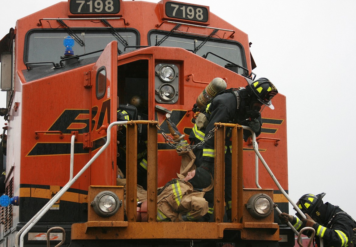 From left, Northern Lakes Firefighter/Medic Bill Daniels, Firefighter Justin Brodin and Firefighter/Medic Matt Dill work to rescue a &#147;patient&#148; from a BNSF Railway locomotive during training. (BRIAN WALKER/Press)