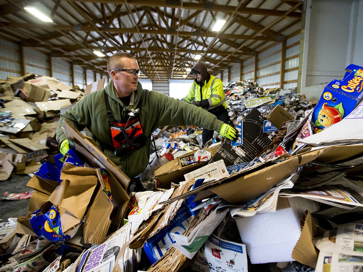 Employee Kyle Scott separates cardboard from a pile garbage Friday afternoon at Coeur d'Alene Garbage. (LOREN BENOIT/Press)