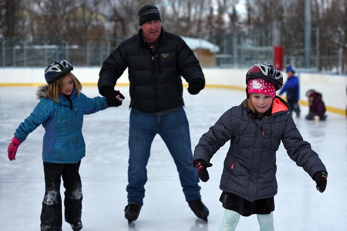 From left, Ella Counts, Mark Freidline, Recreation Superintendent with Kalispell Parks and Recreation, and Olivia Gross enjoy ice skating at Woodland Park during Kalispell Parks and Recreation Freeze Out Camp on Tuesday. (Casey Kreider/Daily Inter Lake)